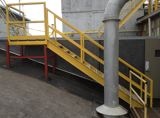 Yellow safety railings leading from lower roof level to upper roof level