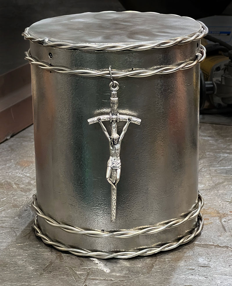stainless steel urn (cylinder) with decorative crown of thorn detail at top/bottom and crucifix in the middle 