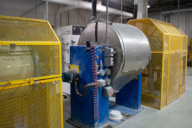 one machine with no machine guard in between two smaller machines wrapped in yellow machine cages