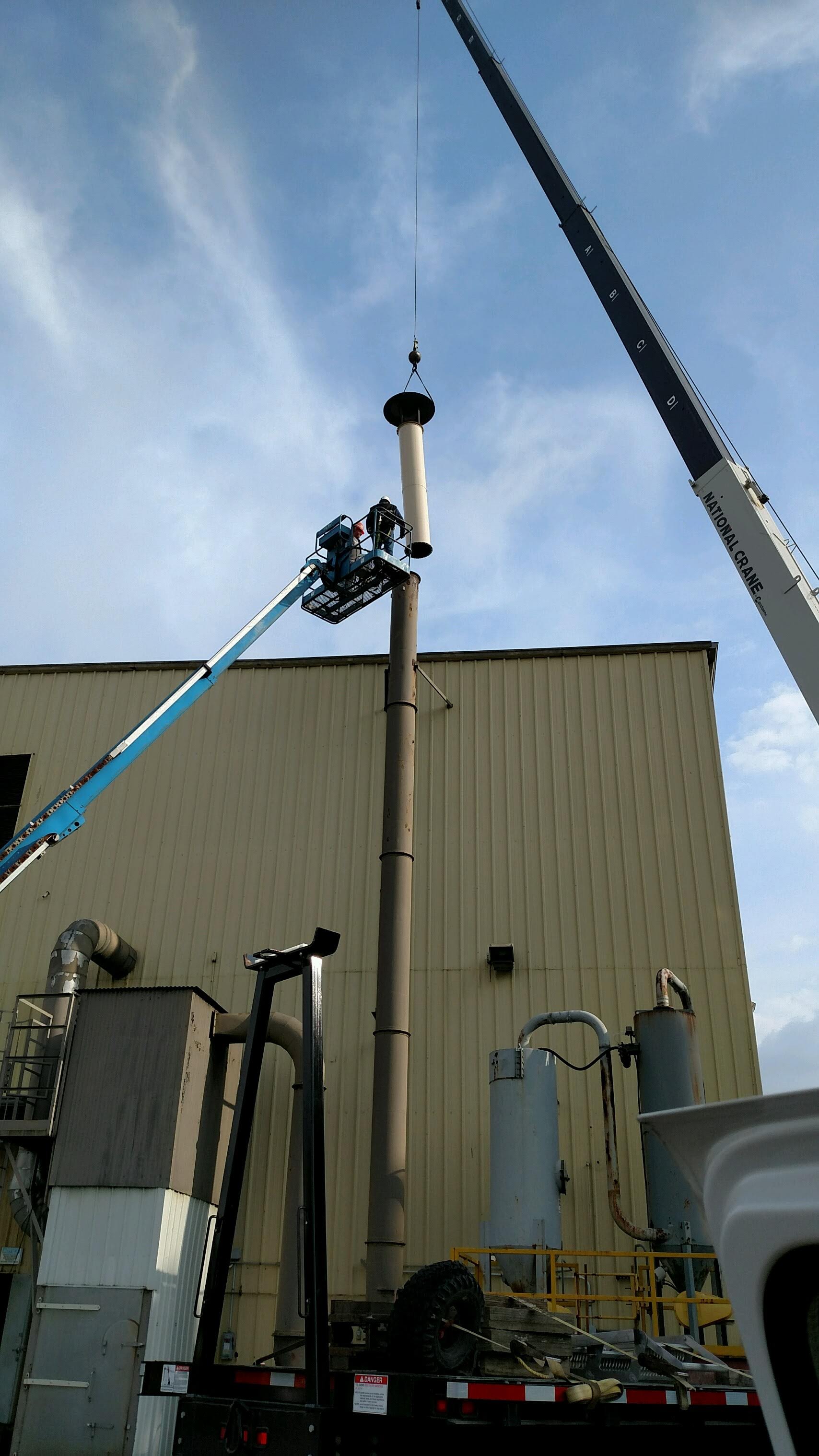 Crane extended, multi-stories high to install a pipe cap