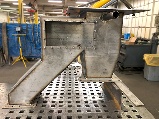 irregular-shaped feed chute in-progress on shop welding table