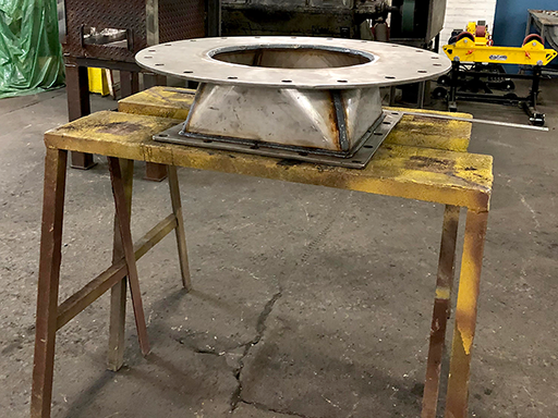 side view of round to square transitional fitting on two sawhorses