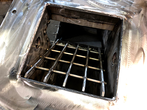 view looking down into of top opening irregular fee chute showing slanted grate inside