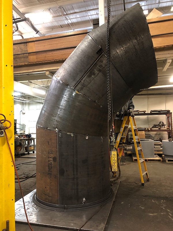 Alternative view of large elbow pipe showing rolled metal plates used to construct it