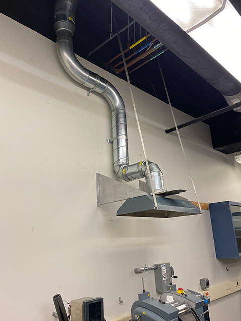 industrial fume hood and piping above a manufacturing station