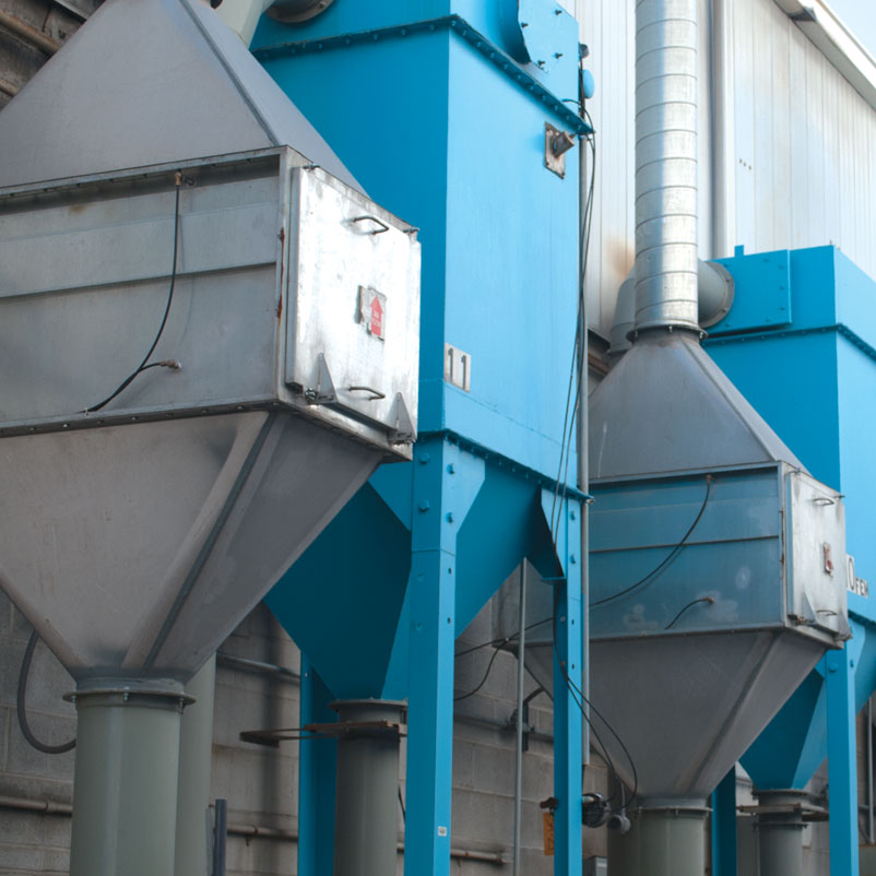 A row of alternating silver HEPA filter units and corresponding dust collectors (painted blue) along a building exterior.